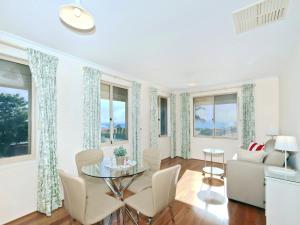 a living room with a table and chairs and windows at Moana Magic - C21 SouthCoast Holidays in Moana