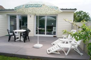 eine Terrasse mit einem Tisch, Stühlen und einem Sonnenschirm in der Unterkunft Le Tiot Gîte in Le Bois de Cise