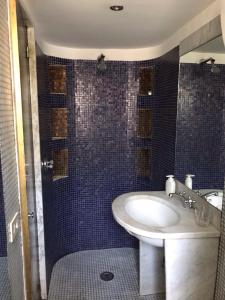 ナポリにあるStudios Galleria Umberto Iの青いタイル張りの壁、洗面台付きのバスルーム