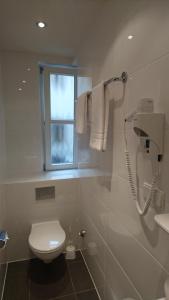 a white bathroom with a toilet and a window at Hotel Kaiserhof am Dom in Regensburg