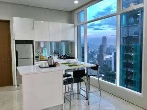 Soho Suites Klcc By Pnut KLCC VIEW في كوالالمبور: مطبخ مع دواليب بيضاء ونافذة كبيرة