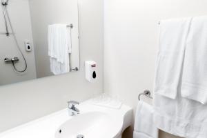 a white bathroom with a sink and a mirror at Fosshotel Nupar in Kálfafell
