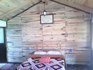 a bedroom with a wooden wall with a bed in it at Cabanas Sierra Nublada in Chignahuapan