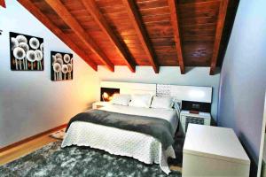 a bedroom with a bed and a wooden ceiling at Casa Encarna Alfoz in Lagoa