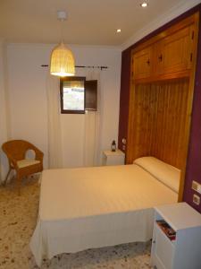 1 dormitorio con 1 cama blanca grande y 1 silla en CASA SAN ANTÓN, en Arcos de la Frontera