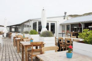 an outdoor patio with wooden tables and chairs at Appartement Dishoek in Koudekerke