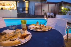 una mesa con dos platos de comida junto a una piscina en La Terrazza, en Aci Castello