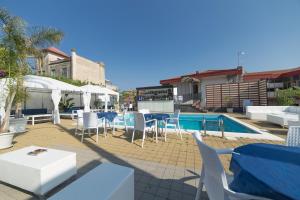 un patio con tavoli, sedie e piscina di La Terrazza ad Aci Castello