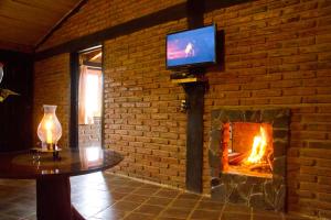 a living room with a fireplace and a tv on a brick wall at Cabanas Sierra Nublada in Chignahuapan