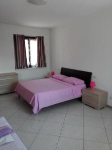 a bedroom with a pink bed and a window at Appartamento Ormeni in Cardano al Campo