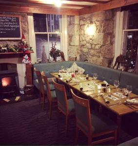 a restaurant with a long table with chairs and a fireplace at The Badger Inn in Carbis Bay