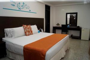 a bedroom with a bed with a desk and a computer at Hotel Arawak Upar in Valledupar