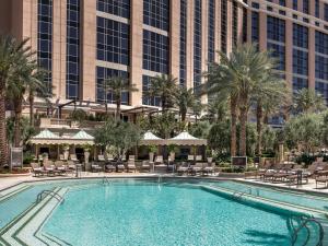 a swimming pool in front of a hotel with palm trees at The Palazzo at The Venetian® in Las Vegas