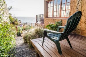 una silla verde sentada en una terraza de madera con vistas al océano en Cinque Colori Bed & Breakfast- Spa, en Algarrobo
