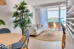 a living room with a table and chairs and a couch at Tingirana Noosa in Noosa Heads