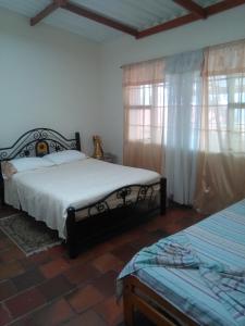 a bedroom with two beds and two windows at Casa finca El Girasol in Guayabal de Síquima +82 photos