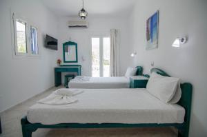 two beds in a room with white walls at Hotel Delfini in Mylopotas