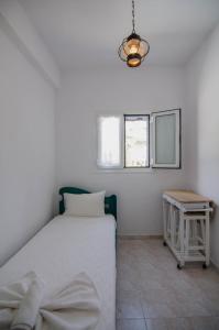 a white bedroom with a bed and a table at Hotel Delfini in Mylopotas