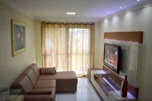 a living room with a couch and a tv at Porto Dreams Flat in Porto De Galinhas