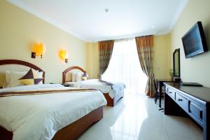 una camera d'albergo con due letti e una televisione di Classy Hotel a Battambang