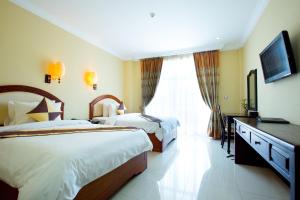 a hotel room with two beds and a television at Classy Hotel in Battambang