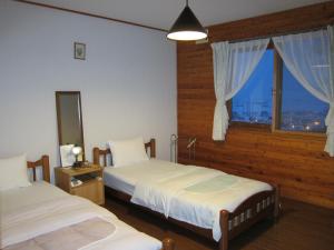 a hotel room with two beds and a window at Pension Yamasan in Nakafurano