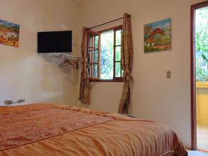 um quarto com uma cama, uma televisão e uma janela em Managua Hills em Manágua