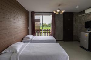 a hotel room with three beds and a window at Nava Resort in Nakhon Nayok