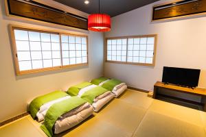 a room with a bed with green pillows and a tv at Bijou Suites Nagomi in Osaka