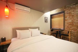 a bedroom with a bed with white sheets and a brick wall at Gray Hotel Busan Station in Busan