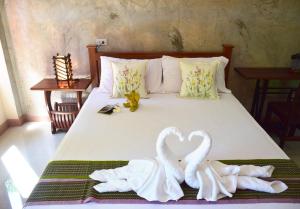 a bed with two towels in the shape of a heart at Siam Guesthouse in Kanchanaburi
