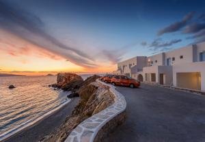 a red car parked next to the ocean at sunset at Vardia Bay Studios in Karavostasi