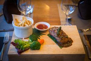 a cutting board with steak and french fries and sauce at Apsara Centrepole Hotel in Siem Reap