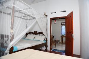a bedroom with a bed with a canopy at Sun Bird Eco Guest Mirissa in Mirissa