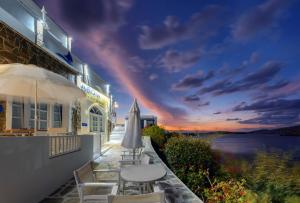 un bâtiment avec une table et des chaises et un coucher de soleil dans l'établissement Vardia Bay Studios, à Karavostasi