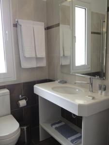 a bathroom with a sink and a toilet and a mirror at Pearl Bay Hotel Apartments in Vrontados