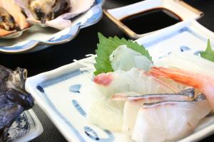 a plate of food with seafood on a table at Minshuku Tsurinoie in Tsushima