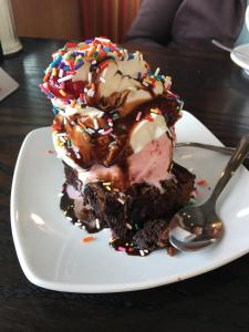 a piece of chocolate cake with ice cream and a spoon at Golden Manor Inn & Suites in Muldraugh