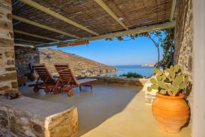 Ganema的住宿－Serifos Dream Houses near the sea，天井配有两把椅子和一张桌子,种植了盆栽植物