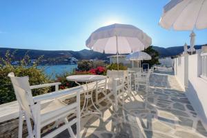 a patio with white chairs and tables and umbrellas at Vardia Bay Studios in Karavostasi