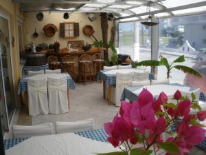 un comedor con mesas blancas y flores rosas en Hotel Europe Inn, en Paralia Katerinis