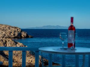una bottiglia di vino seduta su un tavolo accanto all'oceano di Vardia Bay Studios a Karavostasi