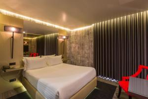 um quarto com uma cama branca e uma cadeira vermelha em Motel Tropicana em Vila Nova de Gaia
