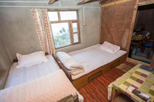 2 camas en una habitación pequeña con ventana en Patlekhet Community Homestay en Patlekhet