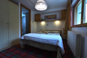 1 dormitorio con cama y lámpara de araña en Hotel Paradisia en Cogne