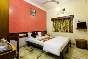 ムンバイにあるHotel Mogul Palace - Near CST Stationの赤い壁のベッドルーム1室(ベッド1台付)