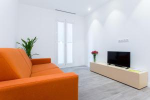 バルセロナにあるCosmo Apartments Marina – Auditoriのリビングルーム(オレンジ色のソファ、テレビ付)