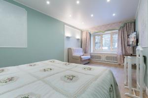a bedroom with a bed and a chair and a window at Feelathome Apartments - Nevsky in Saint Petersburg