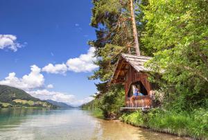 un grupo de personas sentadas en una casa al lado de un río en Haus Kalt, en Weissensee