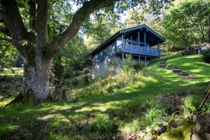a blue house on a hill with a tree at Loch Monzievaird Chalets in Crieff